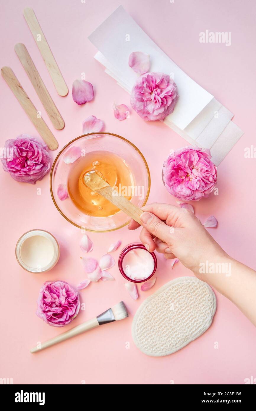 Set for epilation on pink background, flat lay.depilation and beauty concept - sugar paste or wax honey for hair removing with wooden waxing spatula s Stock Photo