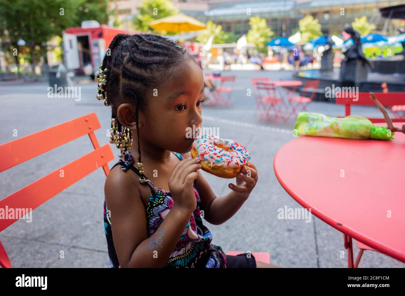 4-5 year old Black girl enjoying a donut on a sunny day. Stock Photo