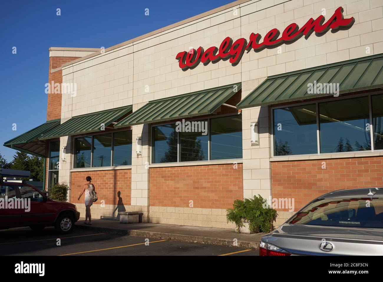 A shopper puts on a face mask before entering the Walgreens pharmacy store in Lake Oswego, Oregon, on Thursday, July 22, 2020, during a pandemic summer. Stock Photo
