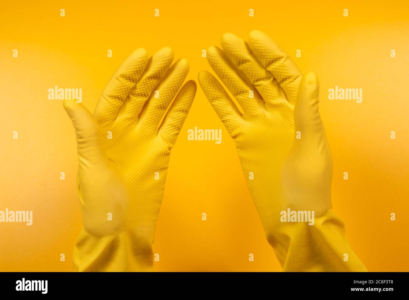 hands in yellow gloves on a yellow background. Stock Photo