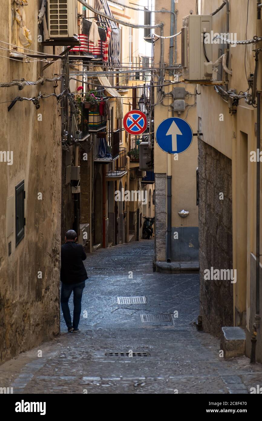man's back in the alleys of Cefalu in Sicily Stock Photo