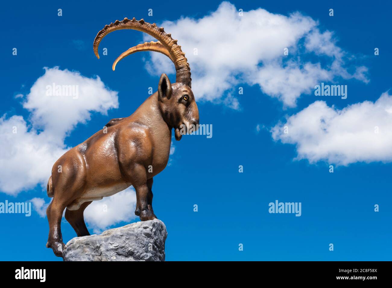 MAYRHOFEN, AUSTRIA - Jun 22, 2019: Sculpture of a mountain goat on a blue sky with white clouds.  The mountain goat is depicted on the Ahorn mountain. Stock Photo