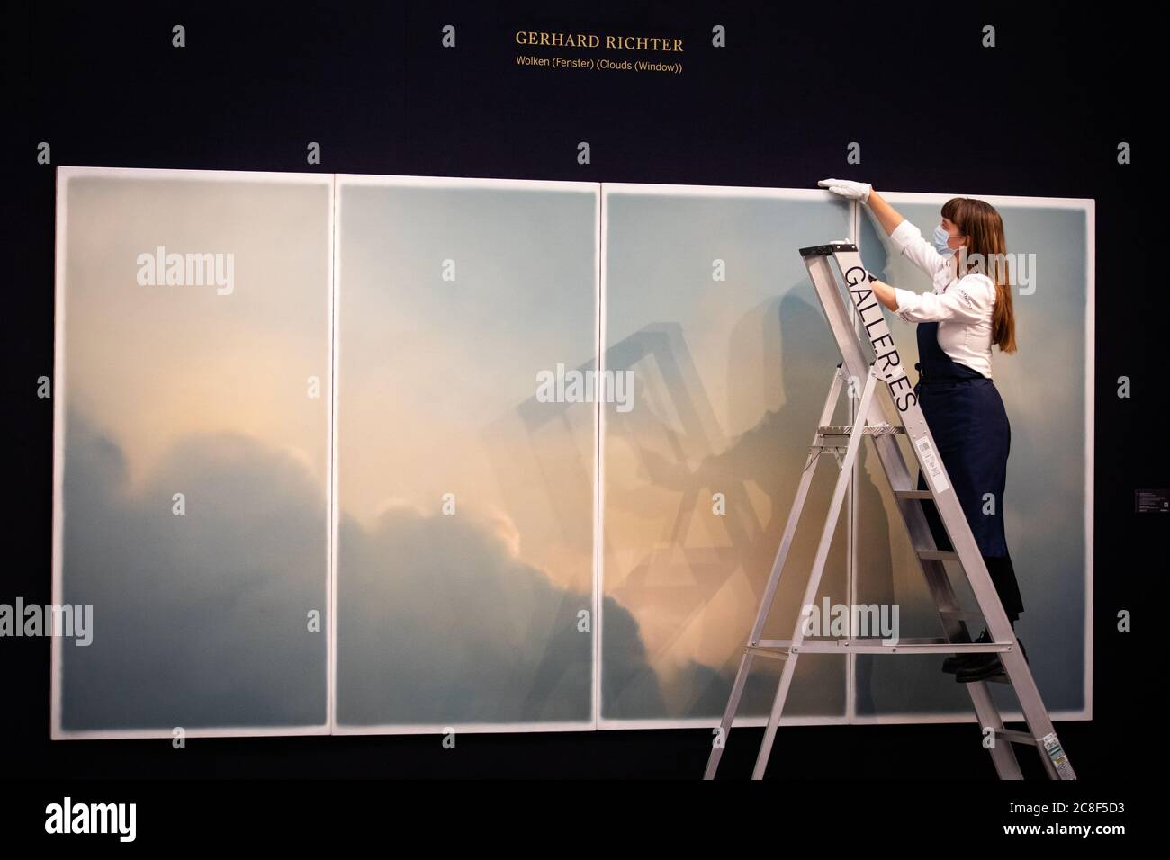 A gallery assistant in front of Wolken (fenster) (Clouds (Window)) by Gerhard Richter, 1970, oil on canvas with an estimate of GBP 9-12 million during a press preview at Sotheby's in London ahead of their 'From Rembrandt to Richter' sale on July 28. Stock Photo