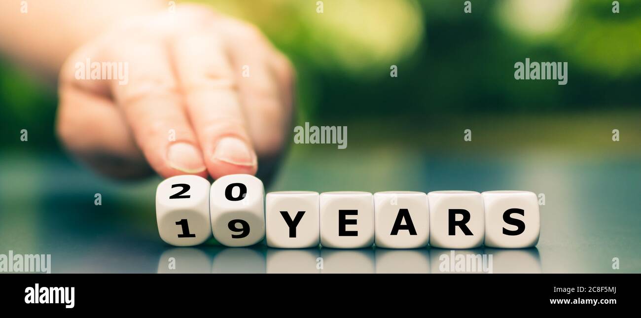 Hand turns dice and changes the expression '19 years' to '20 years'. Stock Photo