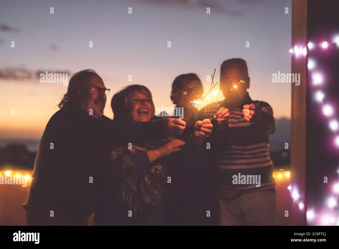 Seniors friends having fun celebrating holidays together outdoor - Happy older people enjoying party laughing on terrace at sunset time Stock Photo