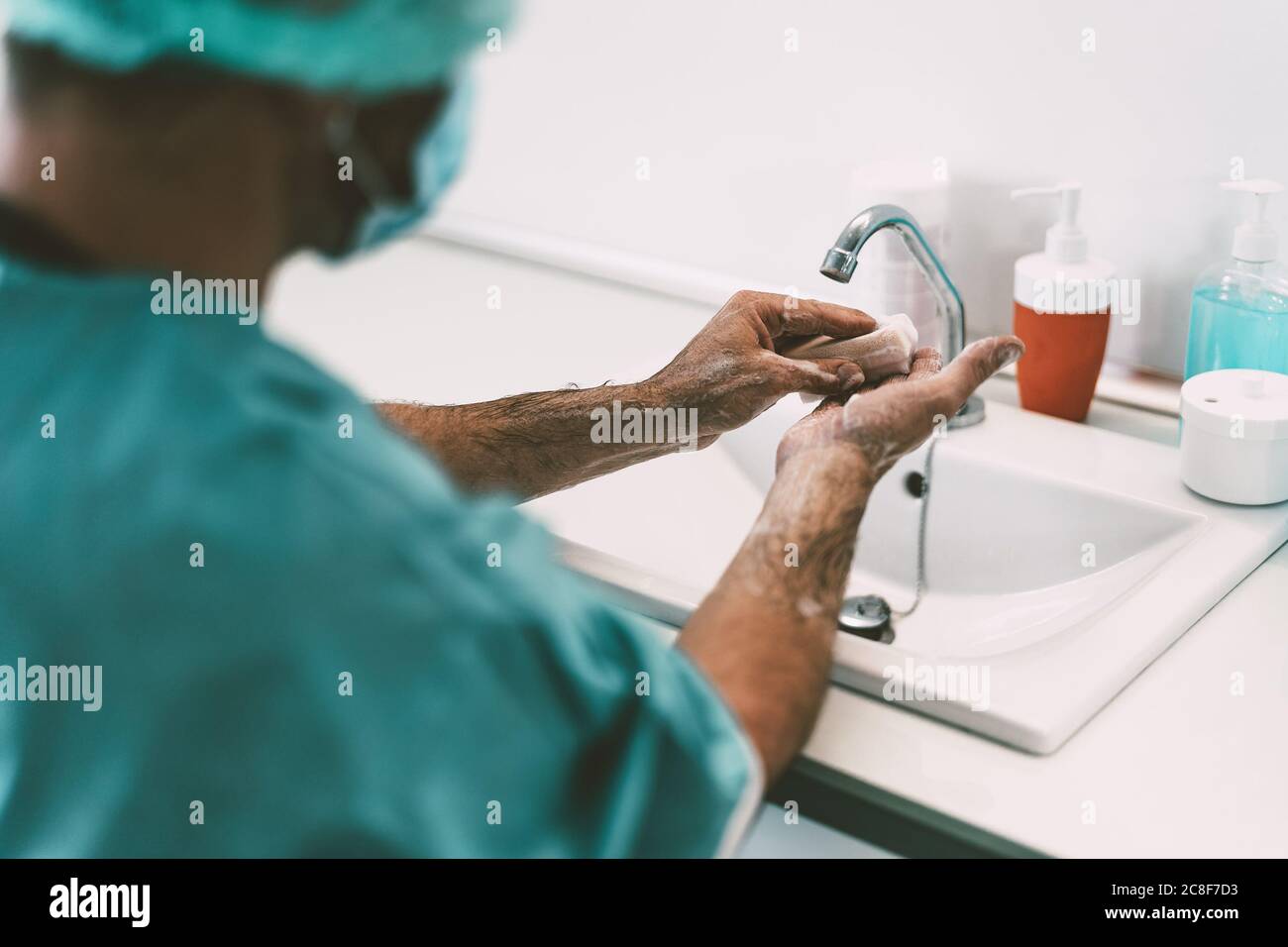 Surgeon washing hands before operating patient in hospital - Medical worker getting ready for fighting against corona virus pandemic Stock Photo