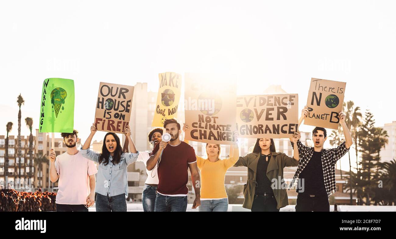 Demonstrators group protesting against plastic pollution and climate change - Multiracial people fighting on road holding banners Stock Photo