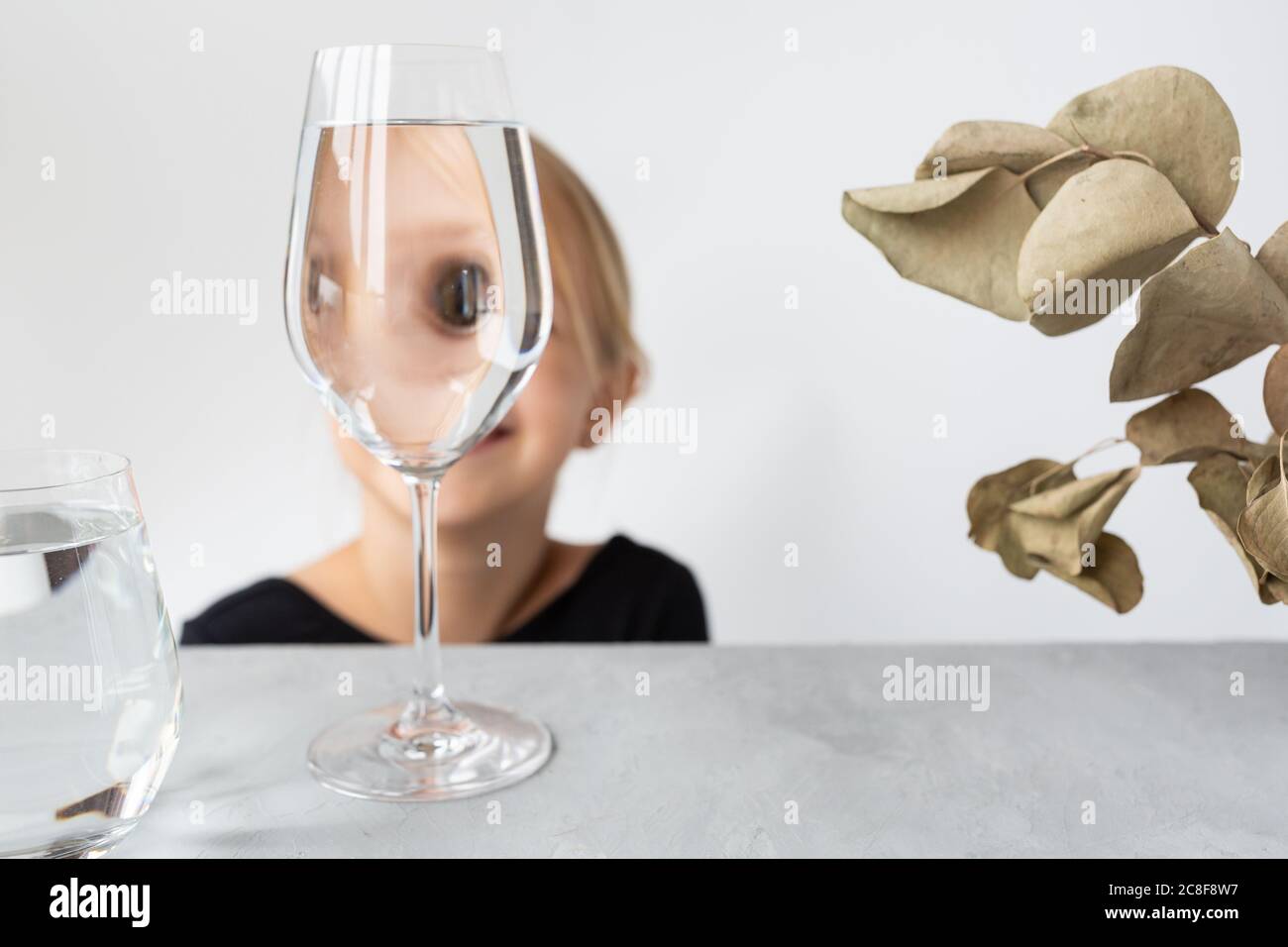 Fashion kid portrait, eye looks through the glass of water. Object