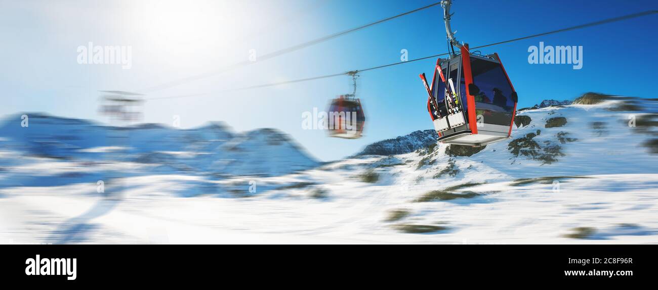 ski lift gondolas against blue sky over snowy mountains at ski resort at Italy Alps on sunny winter day. banner copy space Stock Photo