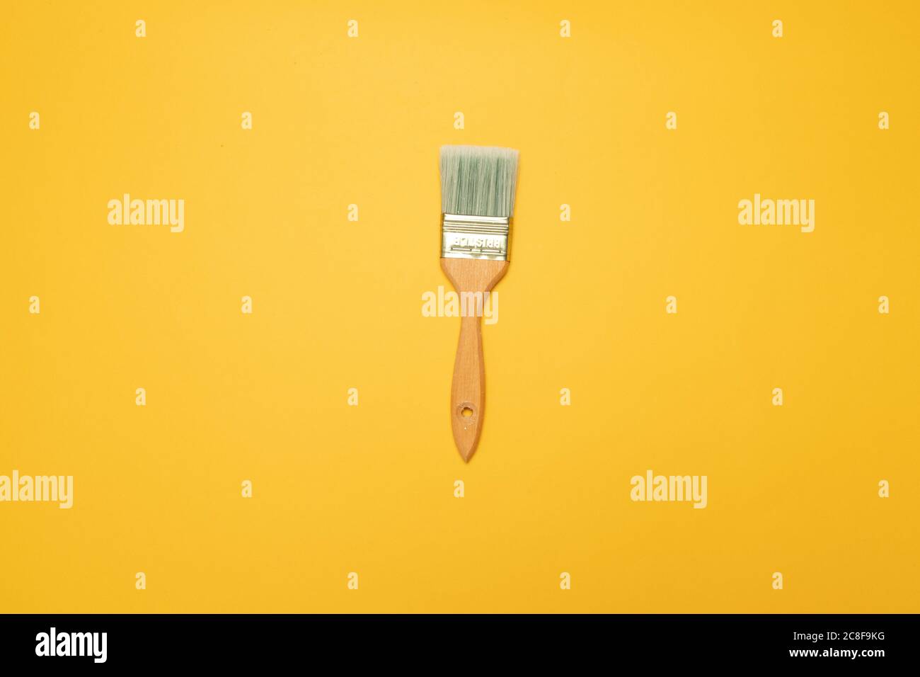 Brush with a nap for painting walls on a yellow background. Top view