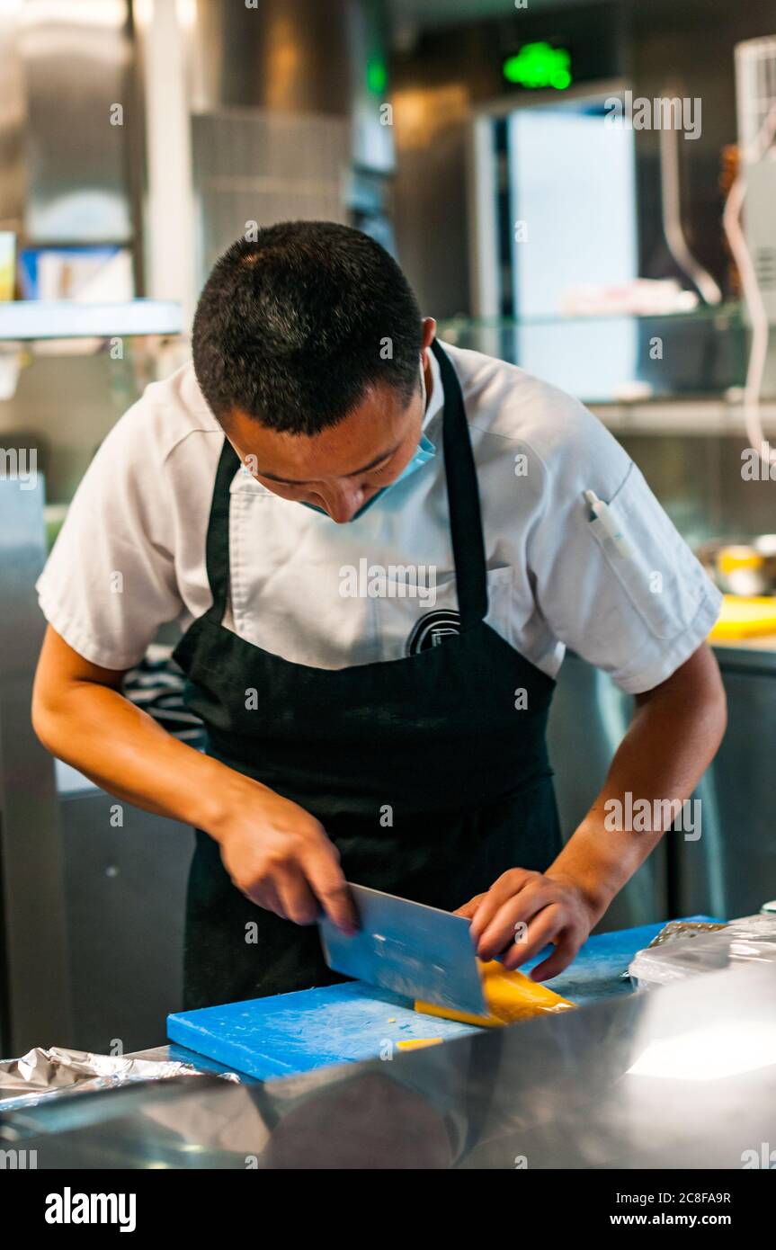A chef cutting cheese in the kitchen at Shanghai Brewhouse in Jing’an District. Stock Photo