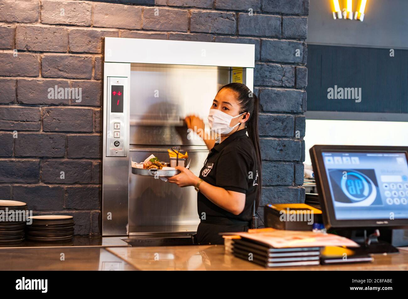 A waitress takes a food order from the dumbwaiter at Shanghai Brewhouse in Jing’an District. Stock Photo