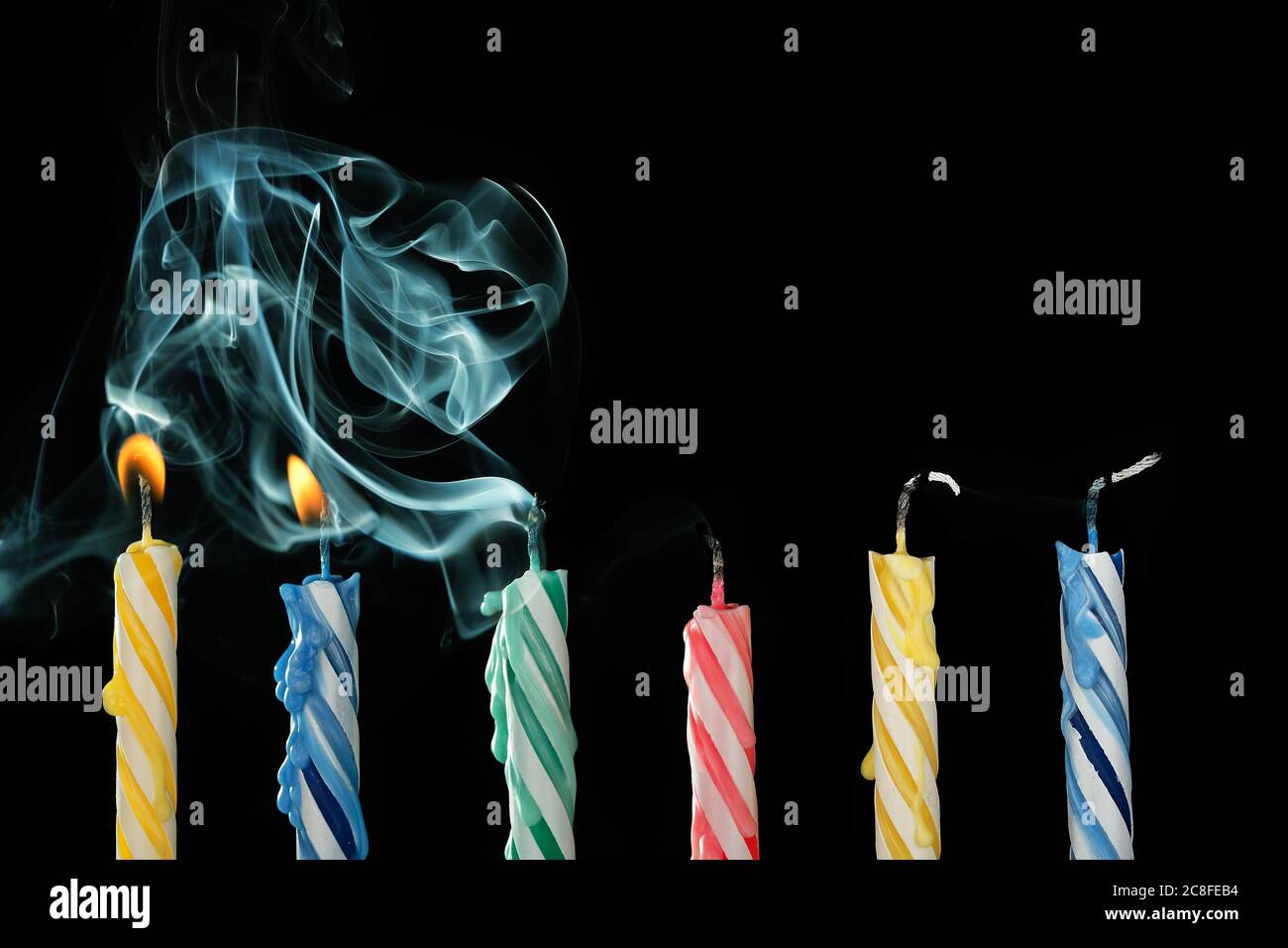 birthday candles that have just been blown out with smoke on black