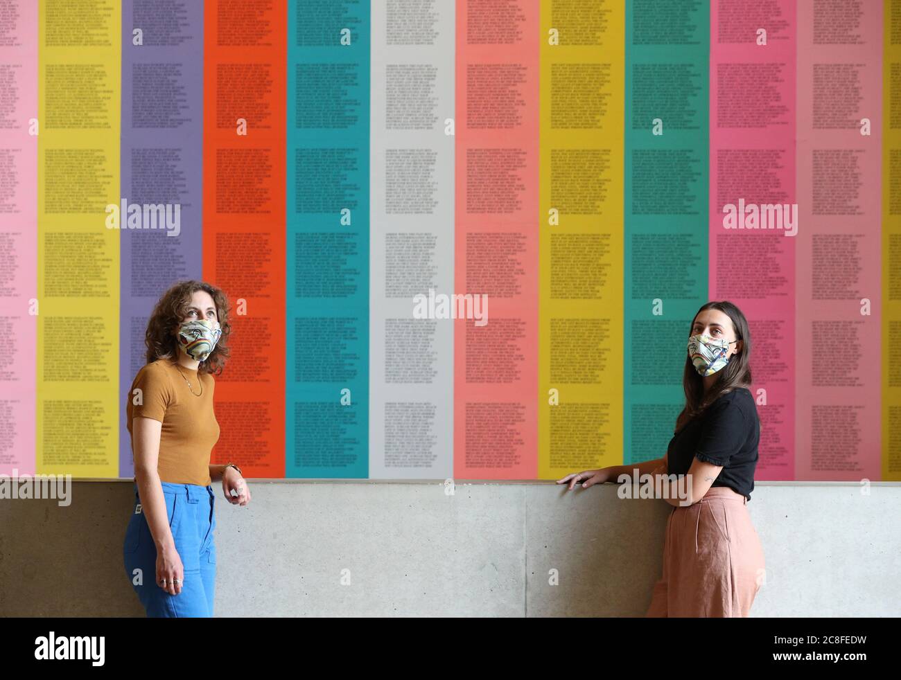 Members of staff wear artwork inspired masks as they stand in front of Jenny Holzer's 'Inflammatory Essays' at the Tate Modern as the gallery prepares to reopen to the public on Monday July 27 following the coronavirus lockdown. Stock Photo