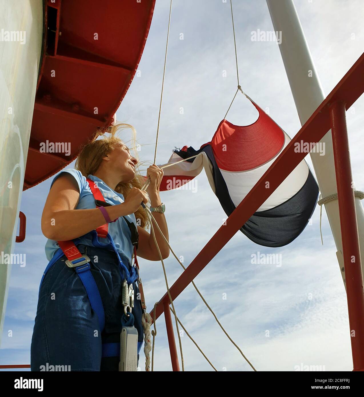 woman hoisting the Flag of the Netherlands on the lighthouse Noordwijk, Netherlands, Noordwijk aan Zee Stock Photo