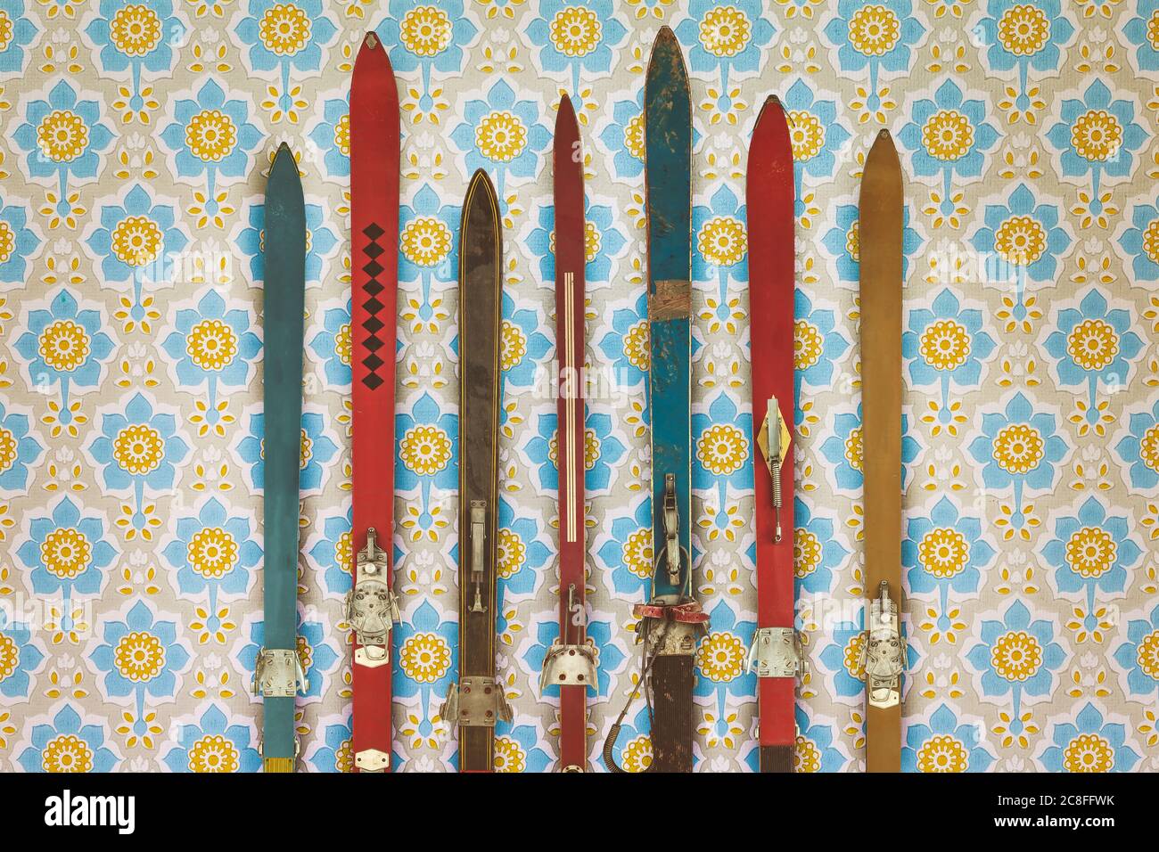 Vintage colorful used skis in front of retro flower wallpaper Stock Photo