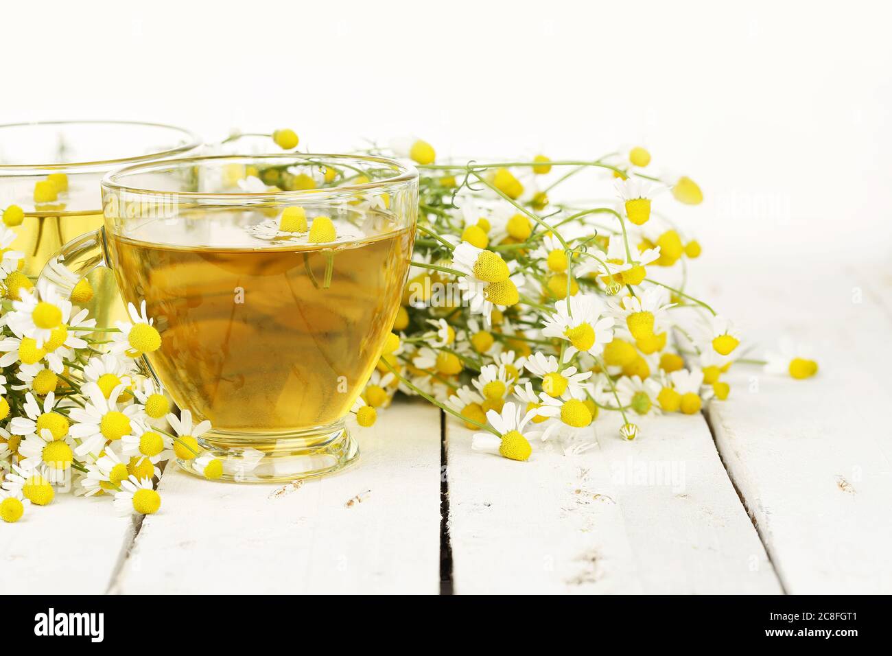 cup of chamomile tea with chamomile flowers on white wooden planks ...