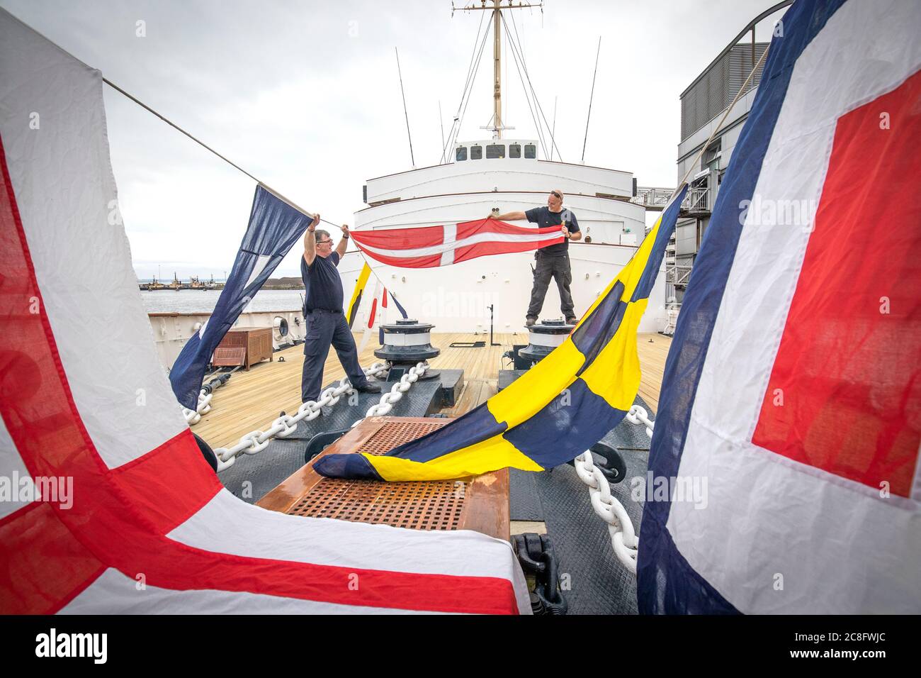 Tony Smith (left) and Rab McAulay, from the maintenance team, raise the dress flags on The Royal Yacht Britannia to mark the Edinburgh visitor attraction reopening to members of the public on Monday 27 July. Stock Photo