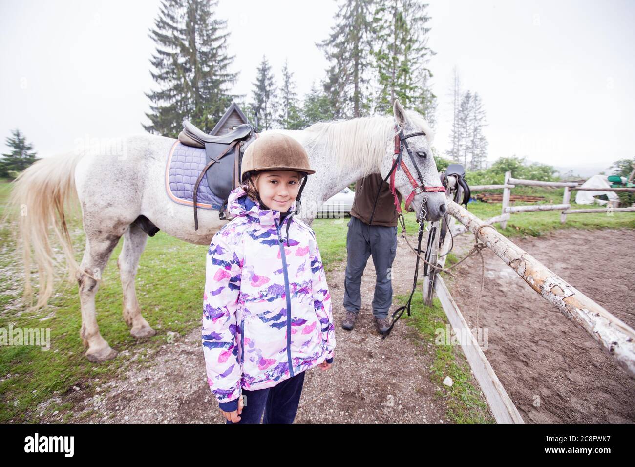 Portrait of smile little girl at ranch, Horseback riding lesson, country landscape Stock Photo