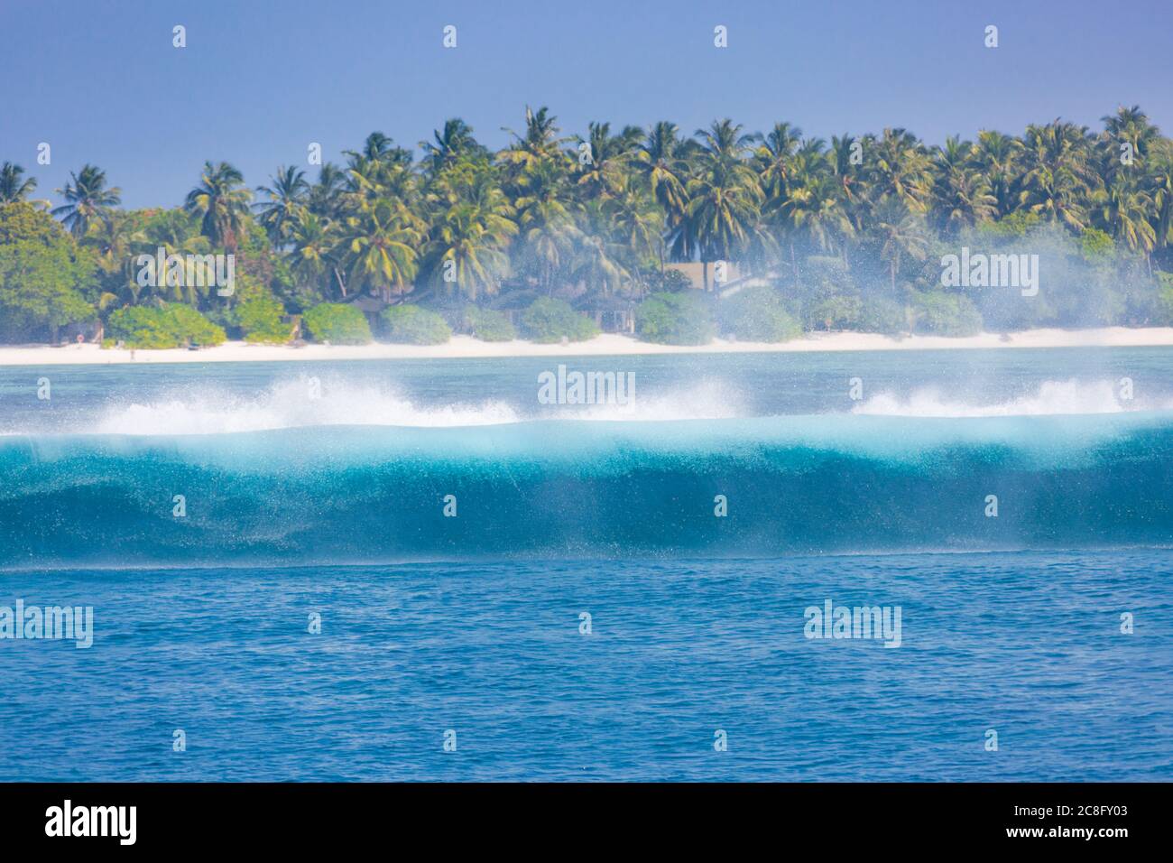 Tropical island with waves splashing. Tropical sea, palm trees and blue sky Stock Photo