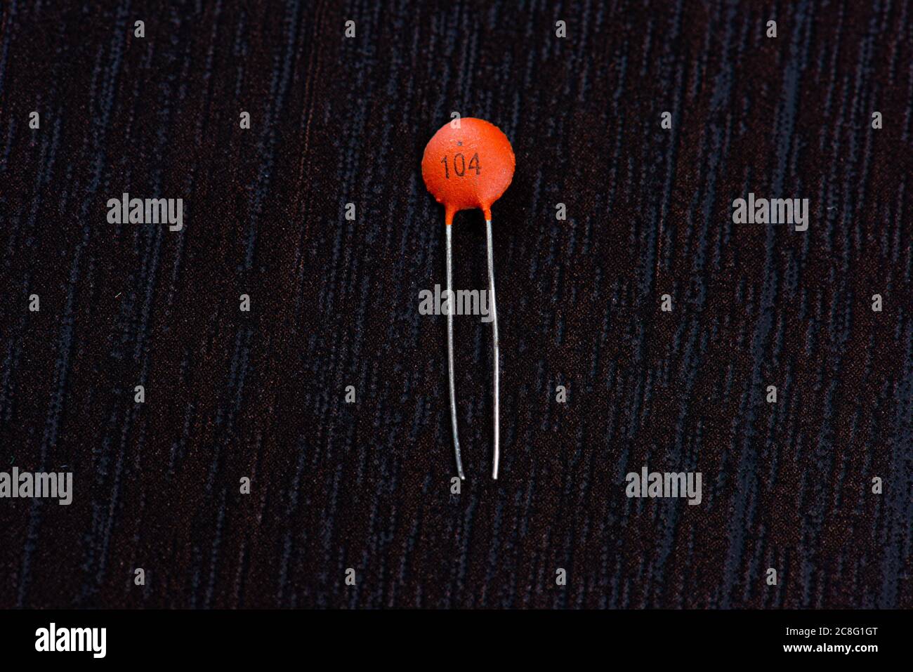 An orange ceramic capacitor on black background Stock Photo - Alamy