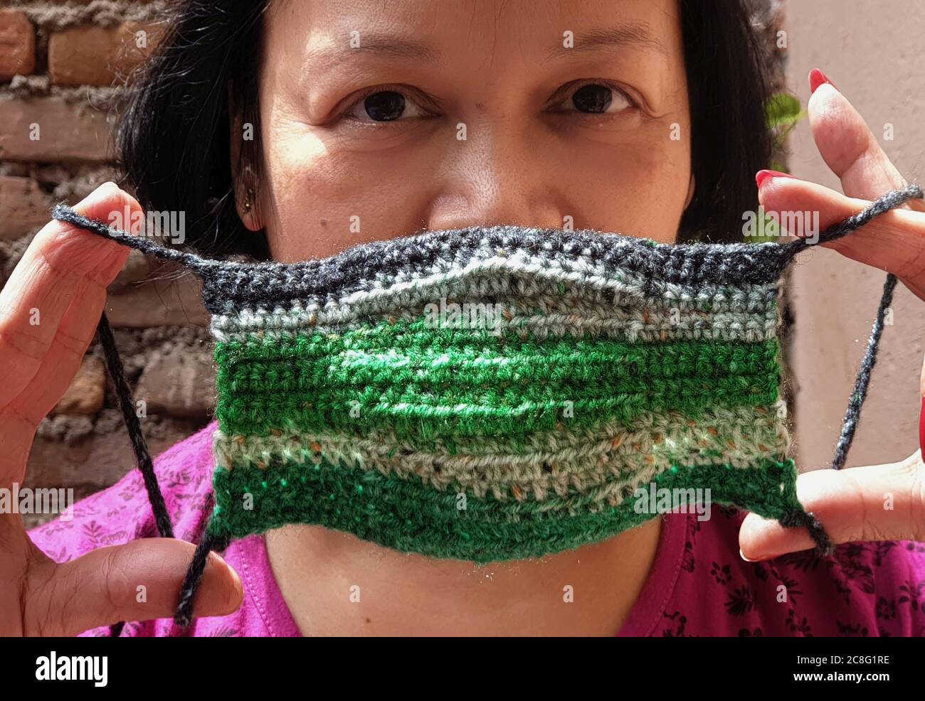 Kathmandu, Nepal. 24th July, 2020. A Nepali woman shows her hand knitted crochet face mask