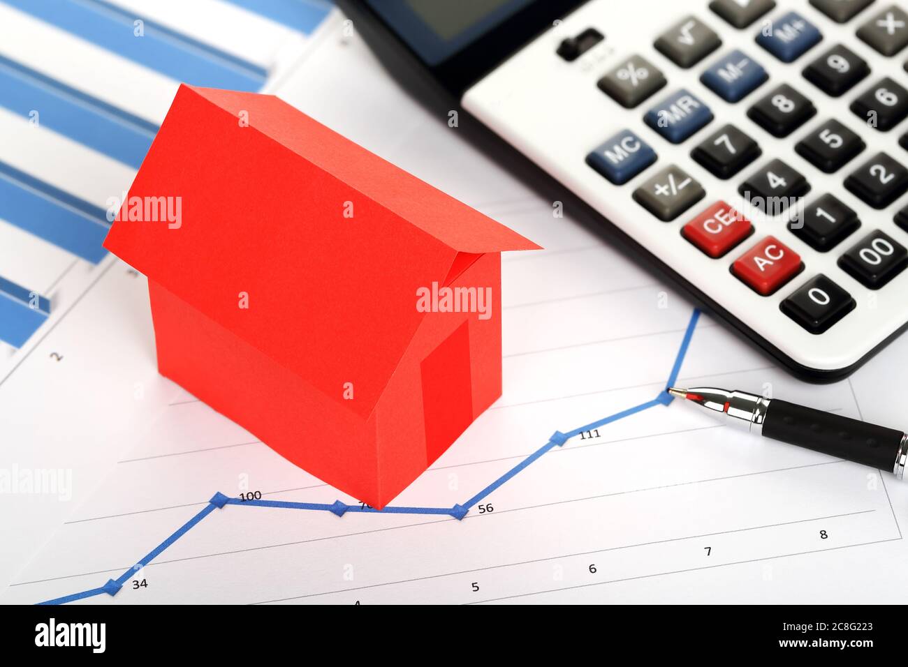 red paper house and calculator on graphs, real estate concept Stock