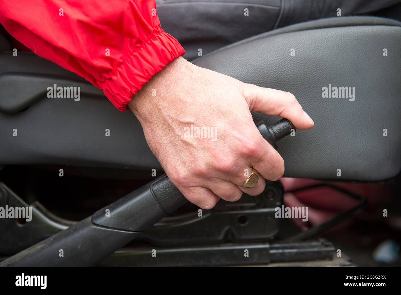 A hand applies a hand brake in a car. Stock Photo