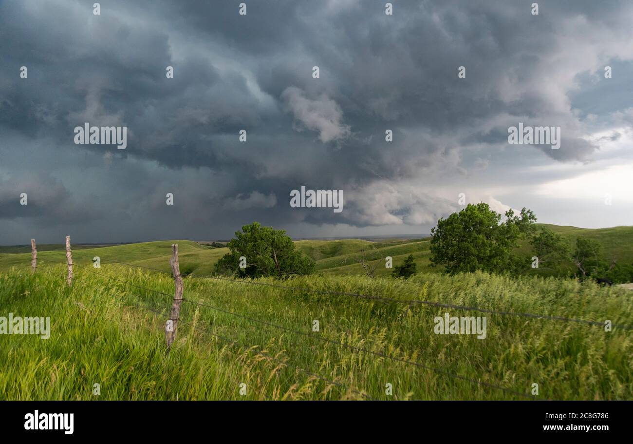 Wall clouds spin below a tornado super-cell hovering and kicking up dust into the updraft base. Stock Photo