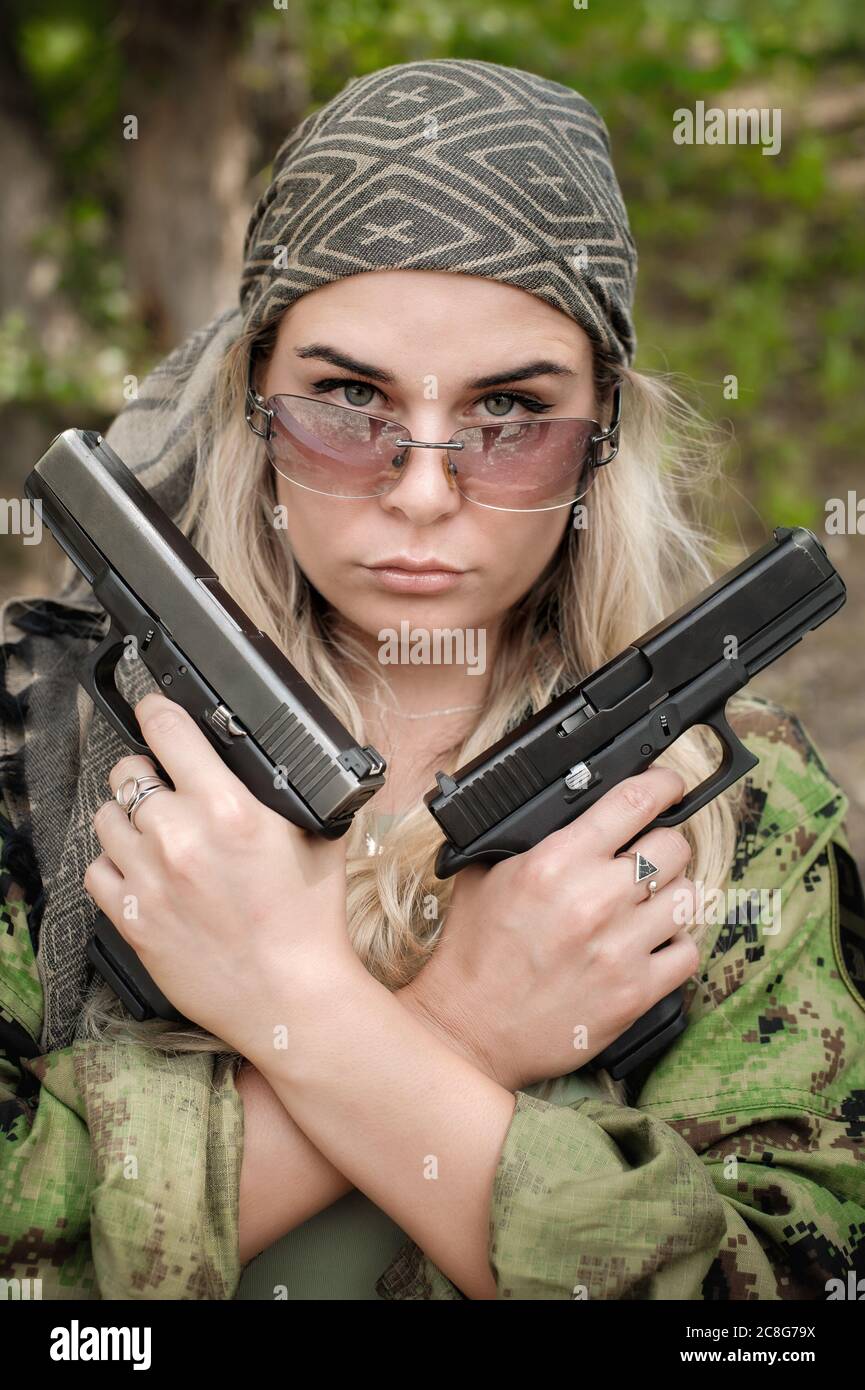 Beautiful and attractive female army soldier posing with gun. Woman