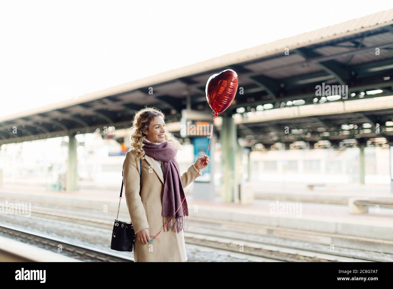 Woman with heart shaped balloon at train station, Firenze, Toscana, Italy Stock Photo