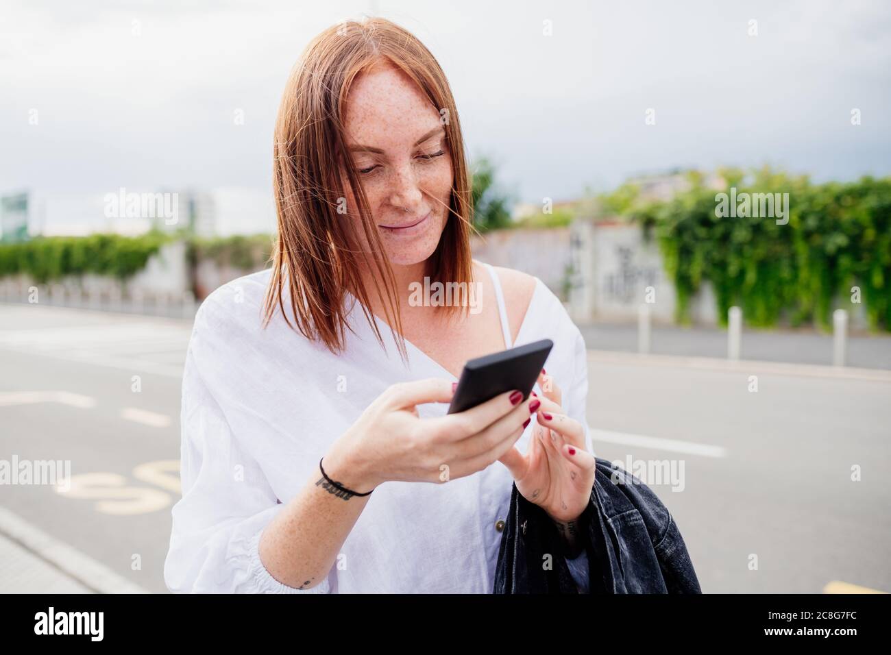 Portrait of woman with long red hair, using mobile phone Stock Photo ...
