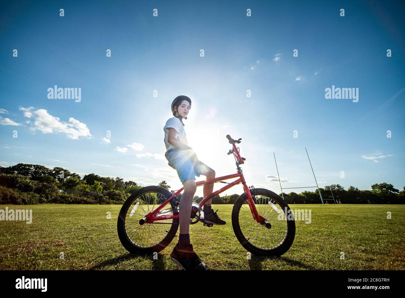 Portrait of boy sitting on his BMX bicycle, wearing cycling helmet. Stock Photo