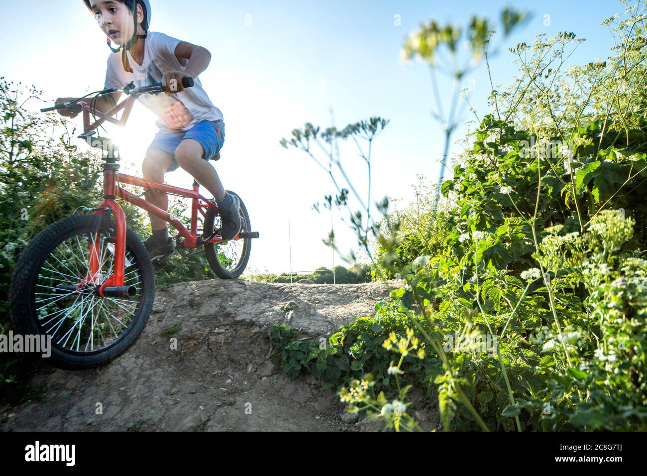 Boy riding down slope on a red BMX bicycle. Stock Photo