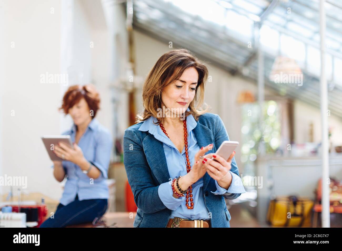Two women, in creative studio, using digital tablet and smartphone Stock Photo