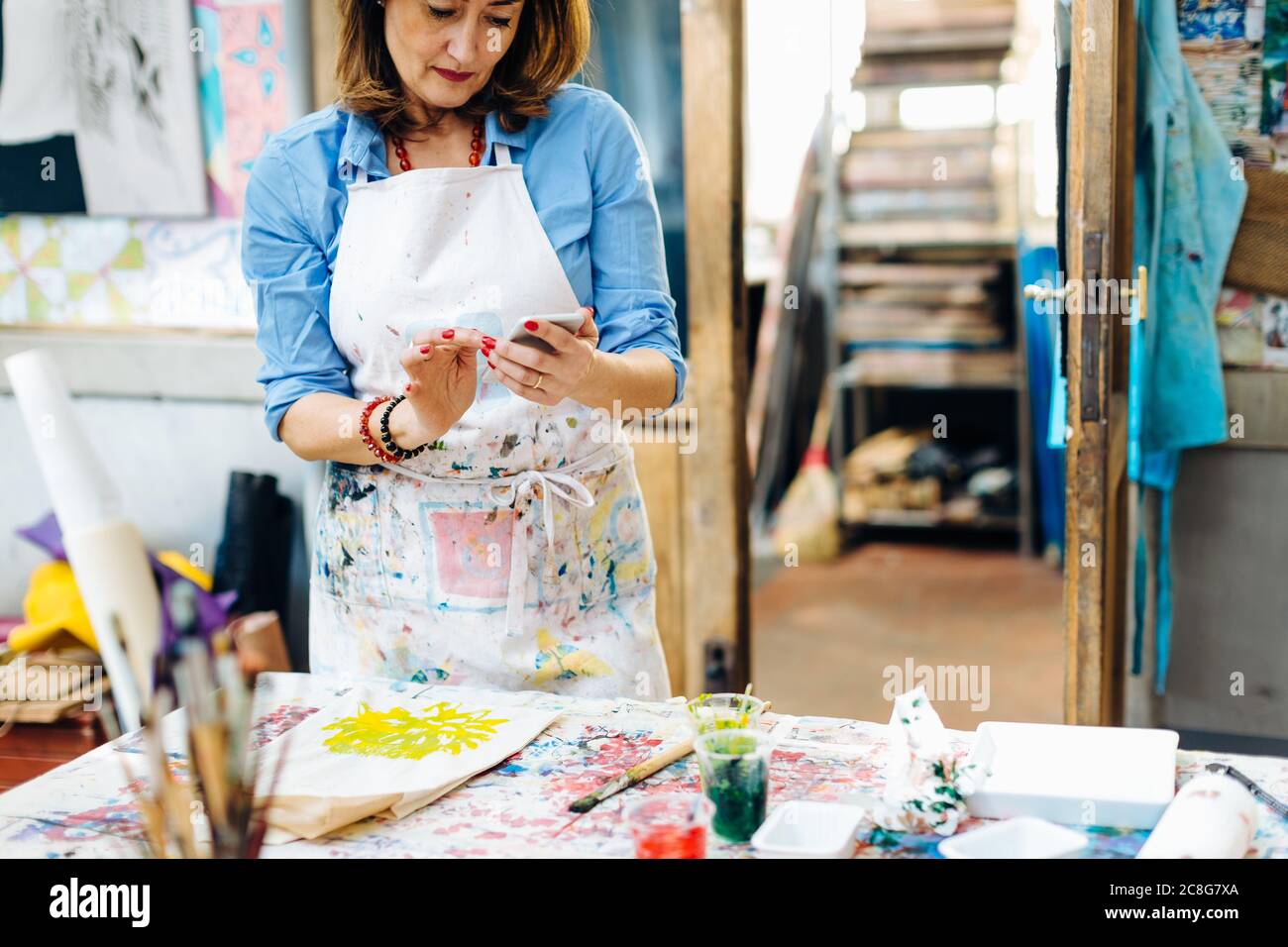 Mature woman in creative studio, using smartphone Stock Photo