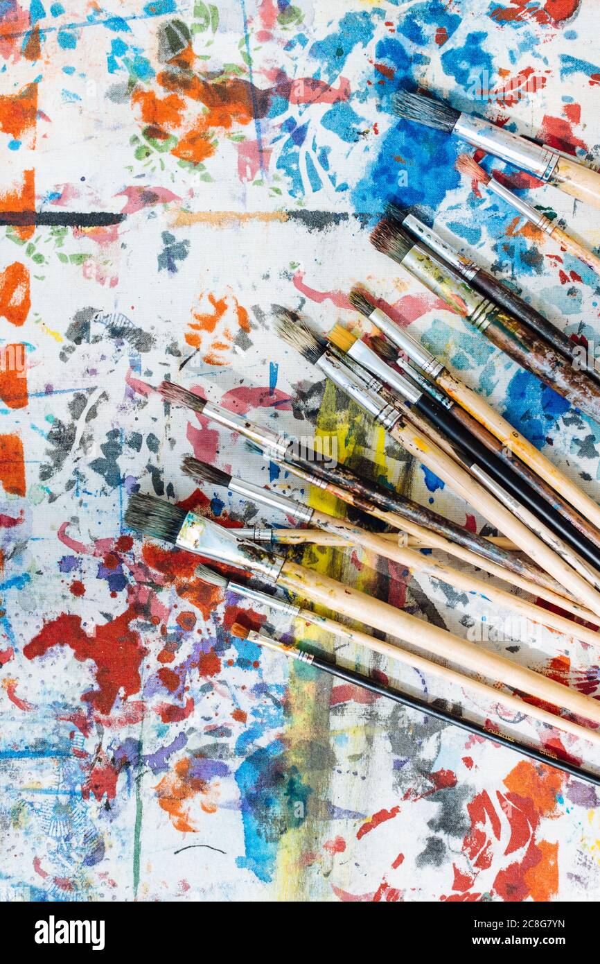 Still life of paintbrushes on colourful painted surface, overhead view Stock Photo