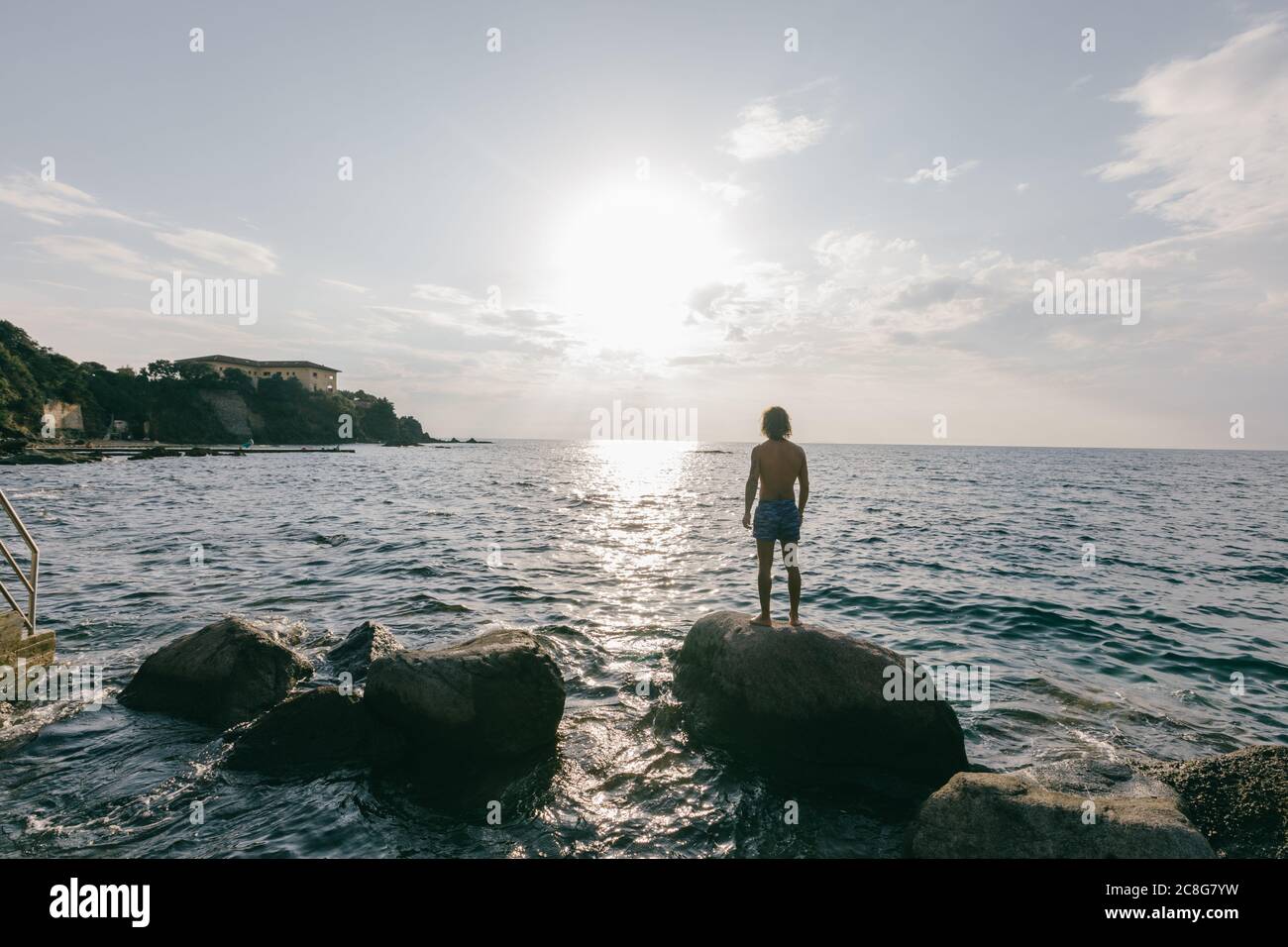 Man standing on rock in sea Stock Photo