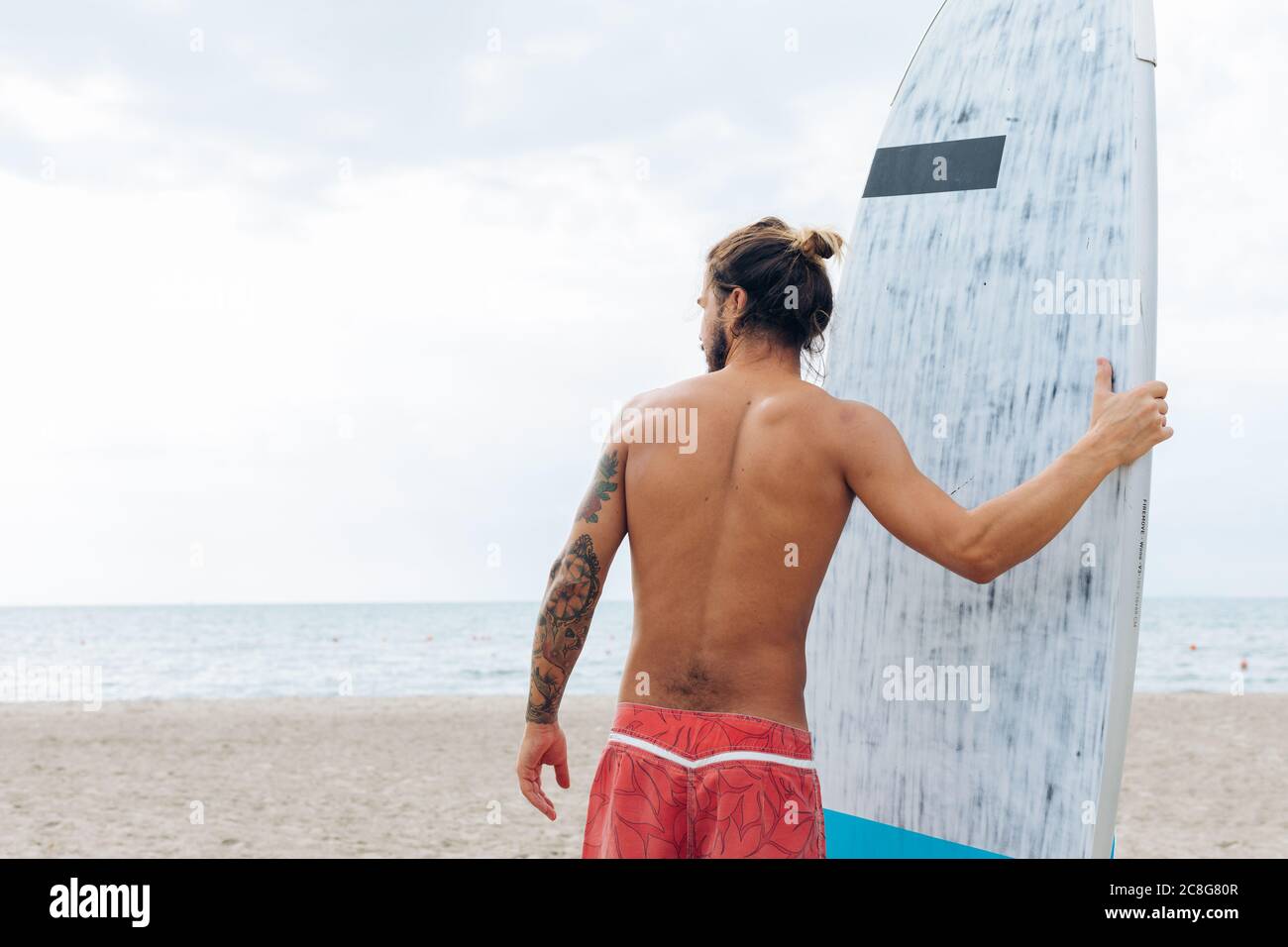 Surfer with surfboard by seaside Stock Photo