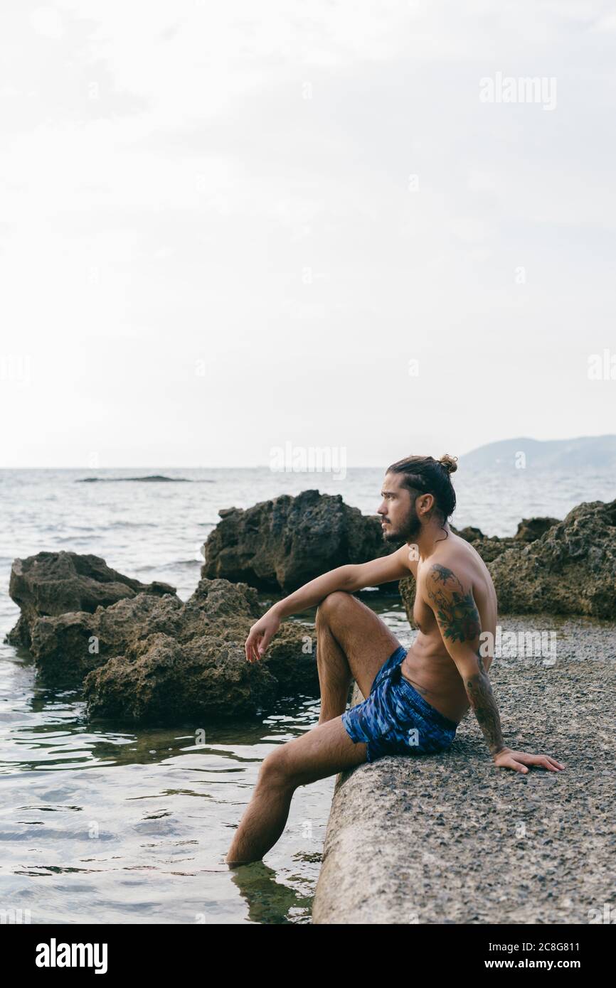 Man sitting on edge of sea Stock Photo