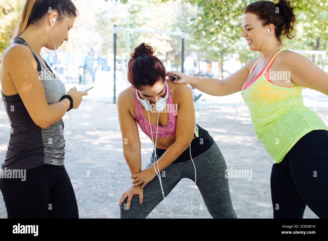 Friends exercising and using cellphone in park Stock Photo