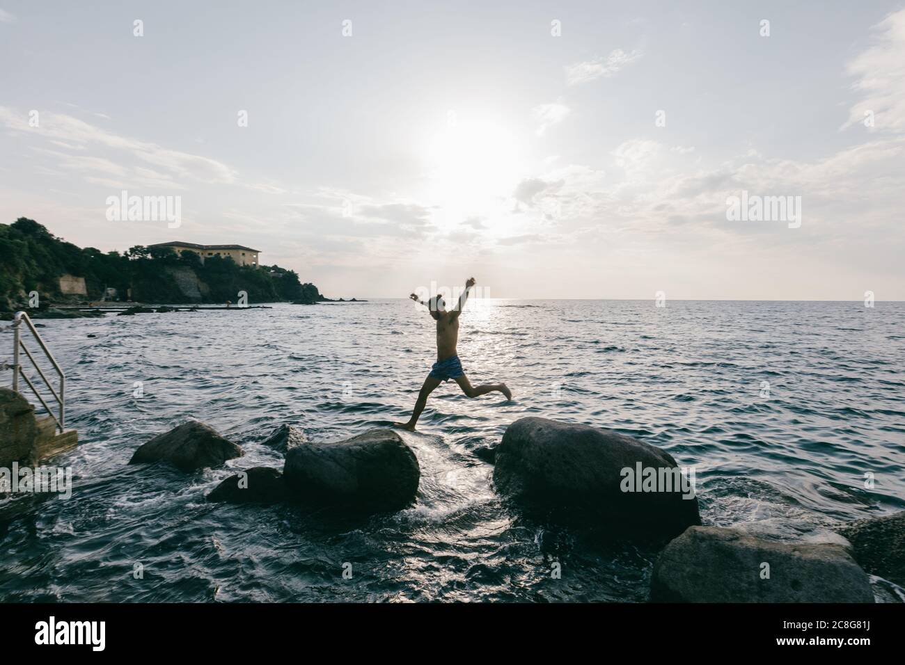 Man jumping from rock to rock in sea Stock Photo