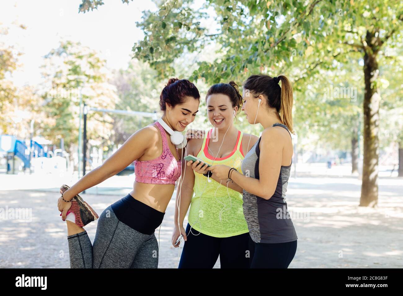 Friends exercising and using cellphone in park Stock Photo