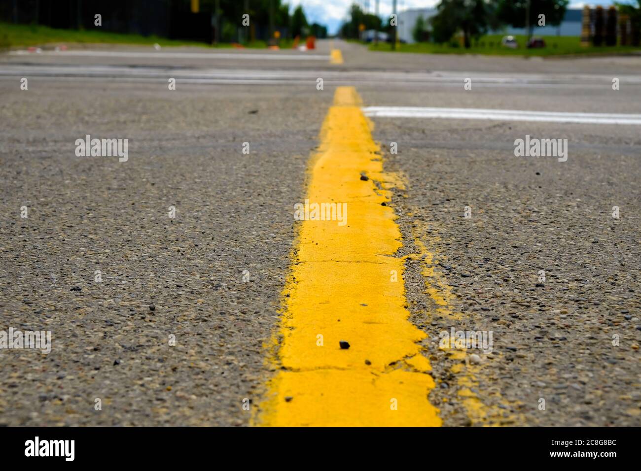 Yellow dividing line on a street in city - Low Angle Stock Photo
