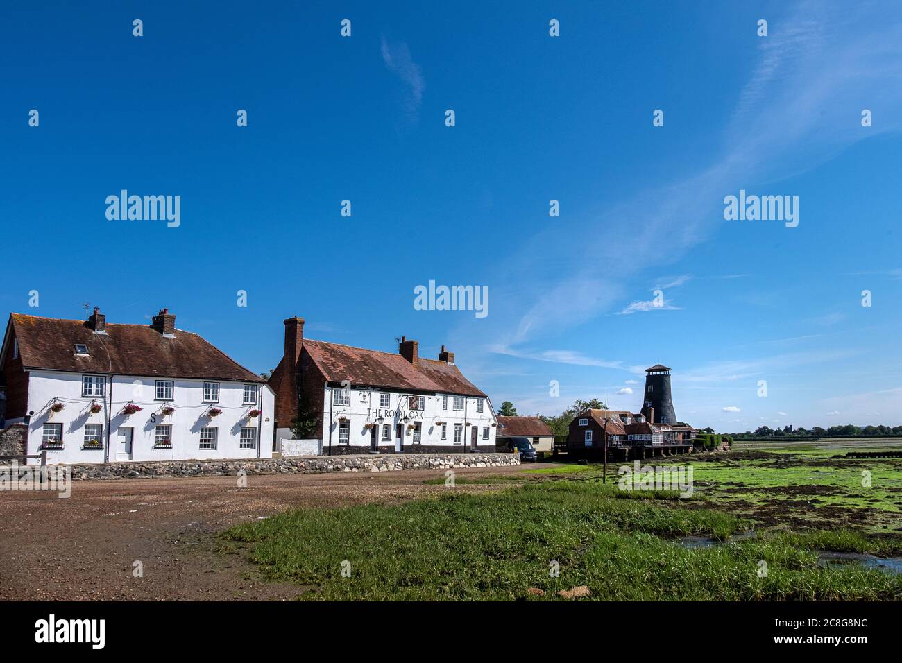The Royal Oak at Langstone Harbour, Hampshire UK against a blue sky and at low tide with the old mill in the background. Stock Photo