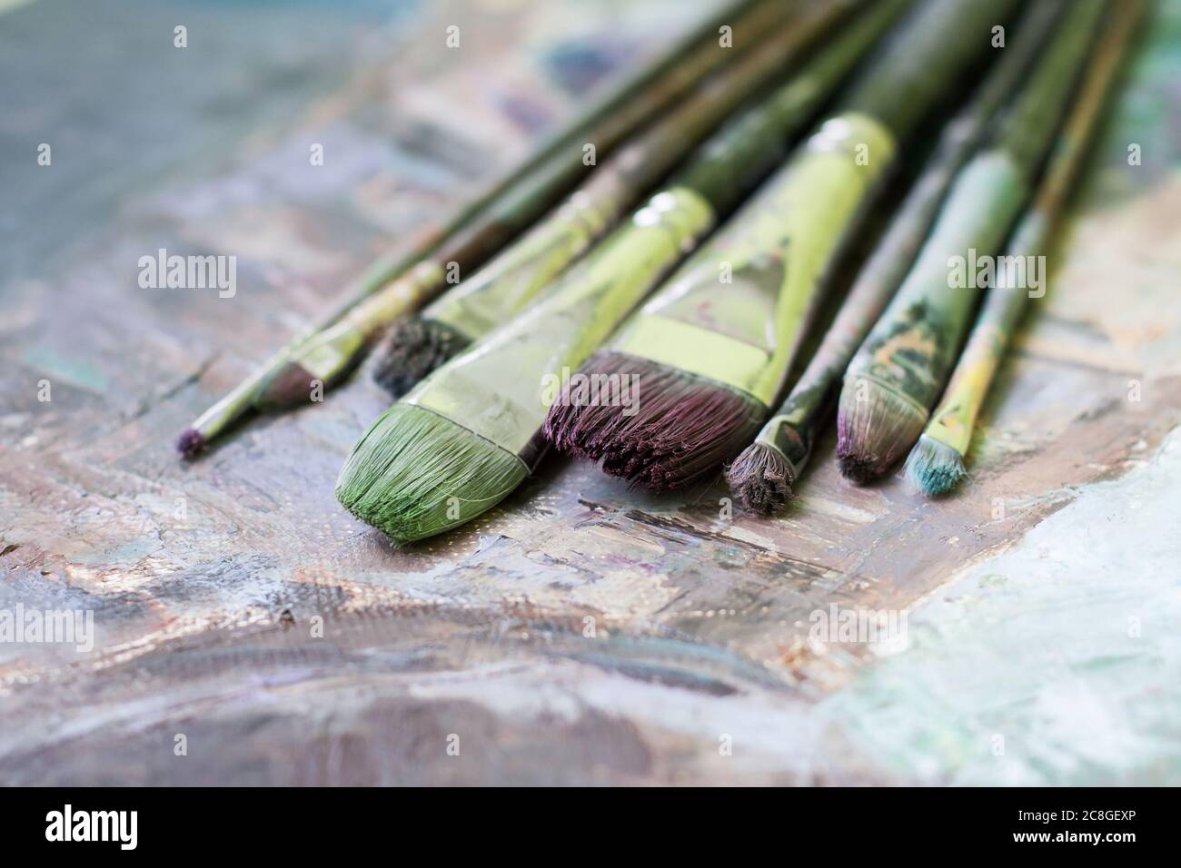 Old oil paint brushes on a painted canvas Stock Photo