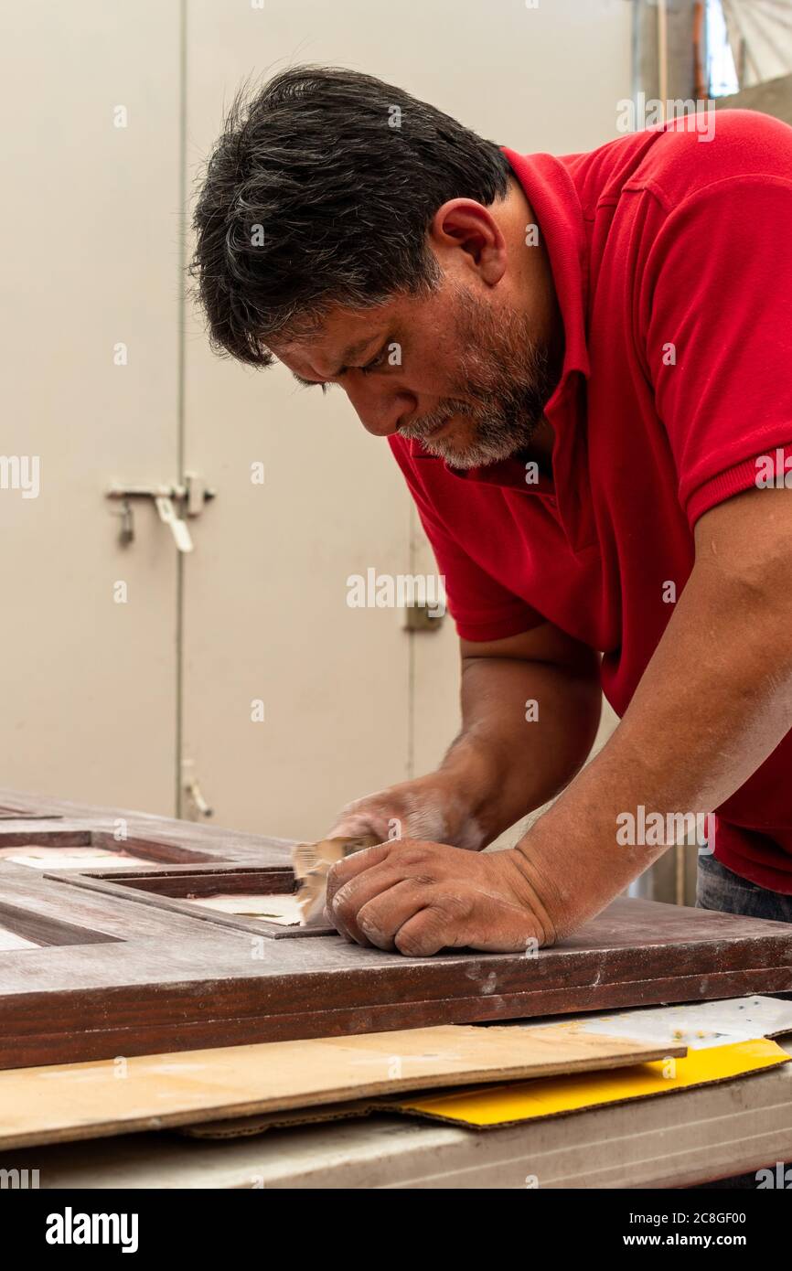 Man fixing a wood door by himself in his house patio Stock Photo