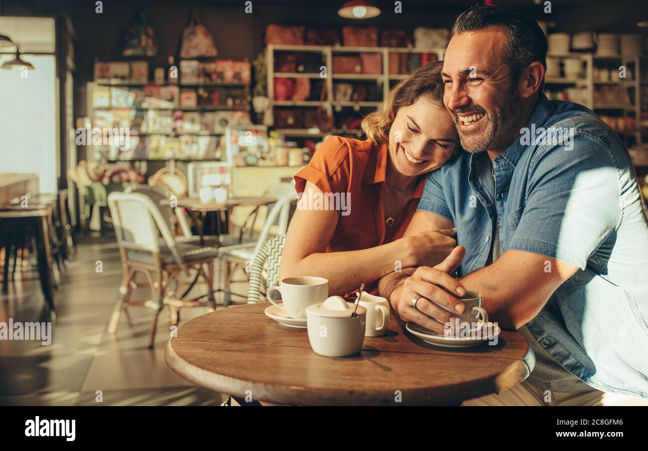 Couple spending quality time together in a coffee shop. Man and woman sitting at cafe table and smiling. Stock Photo