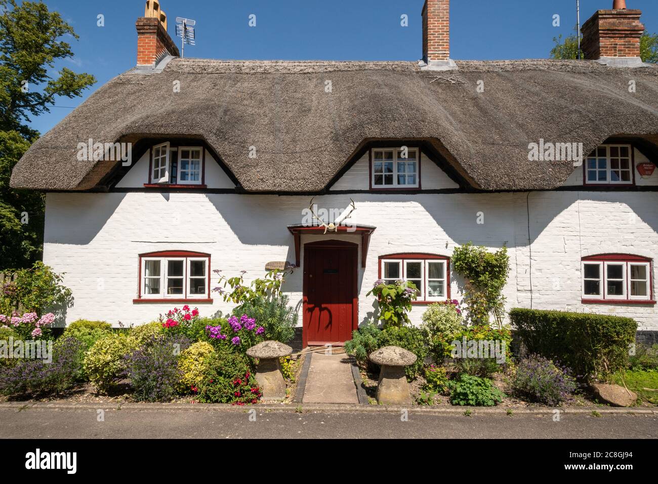 Thatched cottage called Antlers Cottage with deer antlers over the door, Wherwell, Hampshire, UK Stock Photo