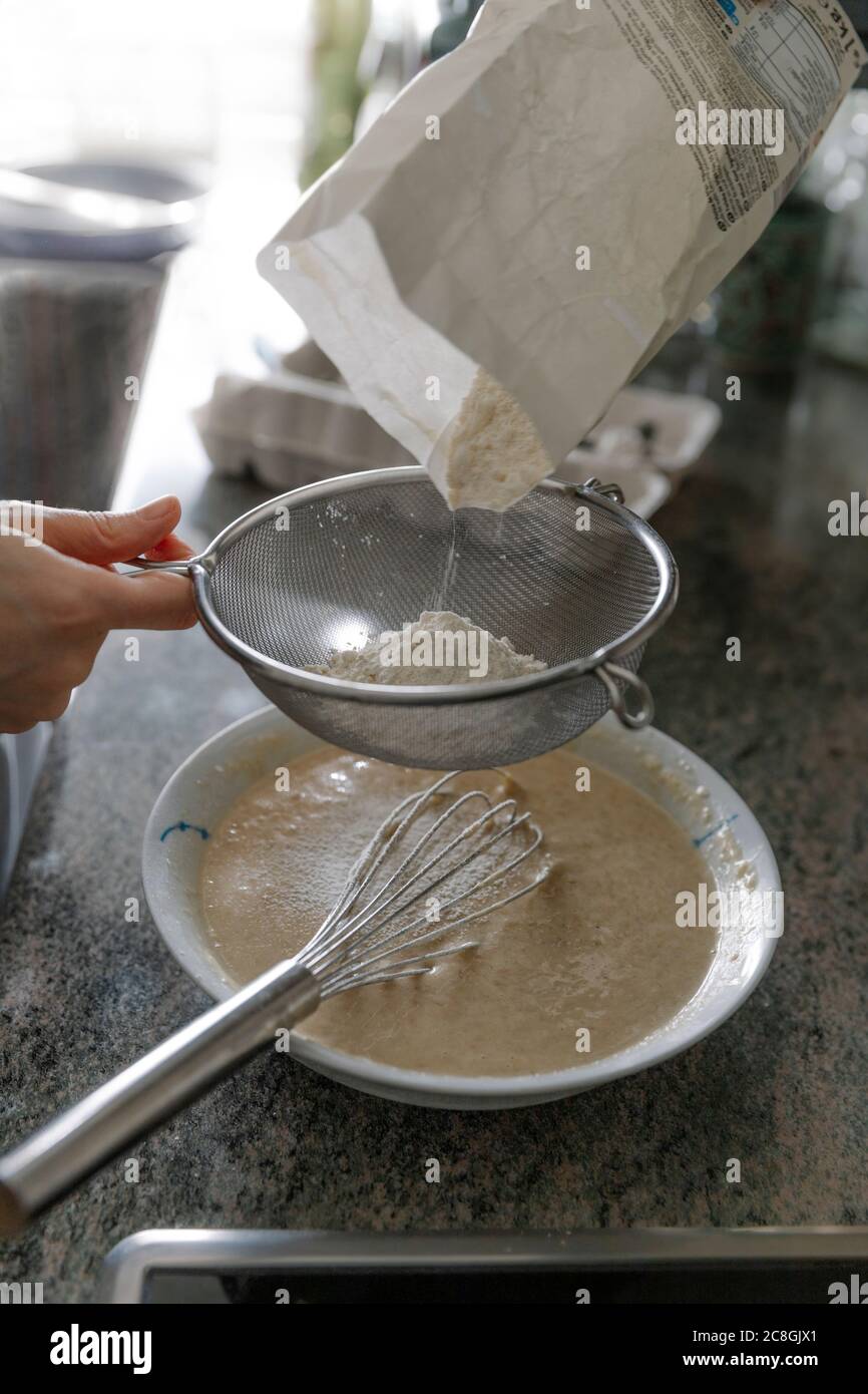 High angle of anonymous person sieving flour while cooking pastry Stock